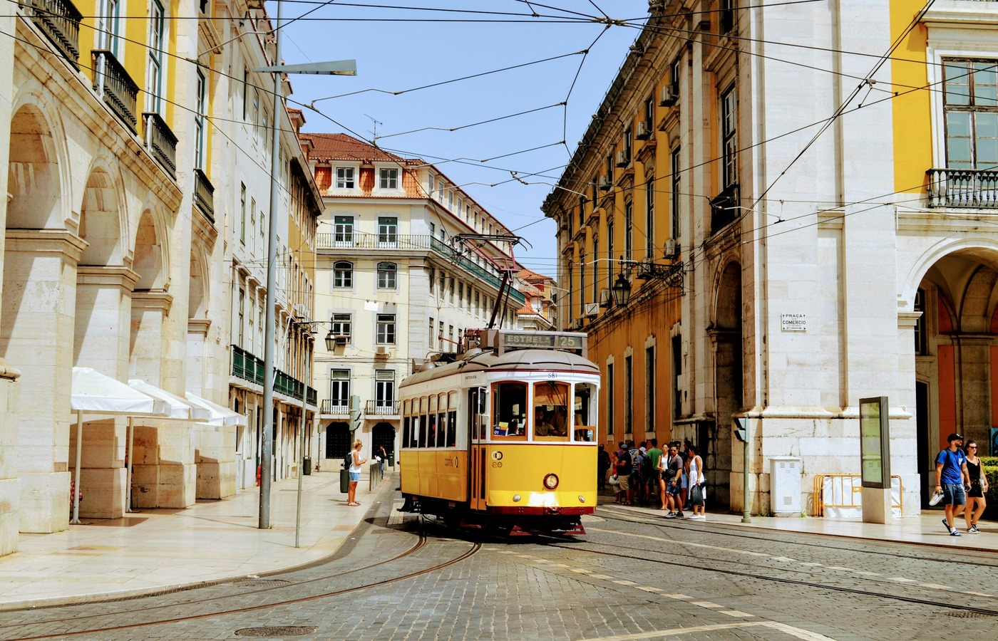 Yellow tram passing through a street lined with historic buildings in Lisbon