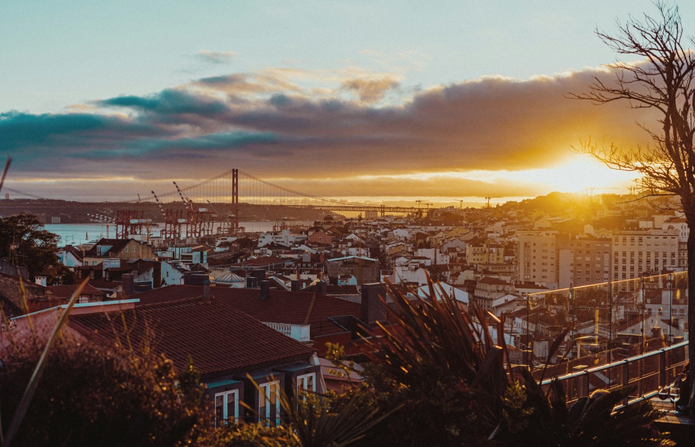 Lisbon rooftops and the 25 de Abril Bridge in warm sunset light