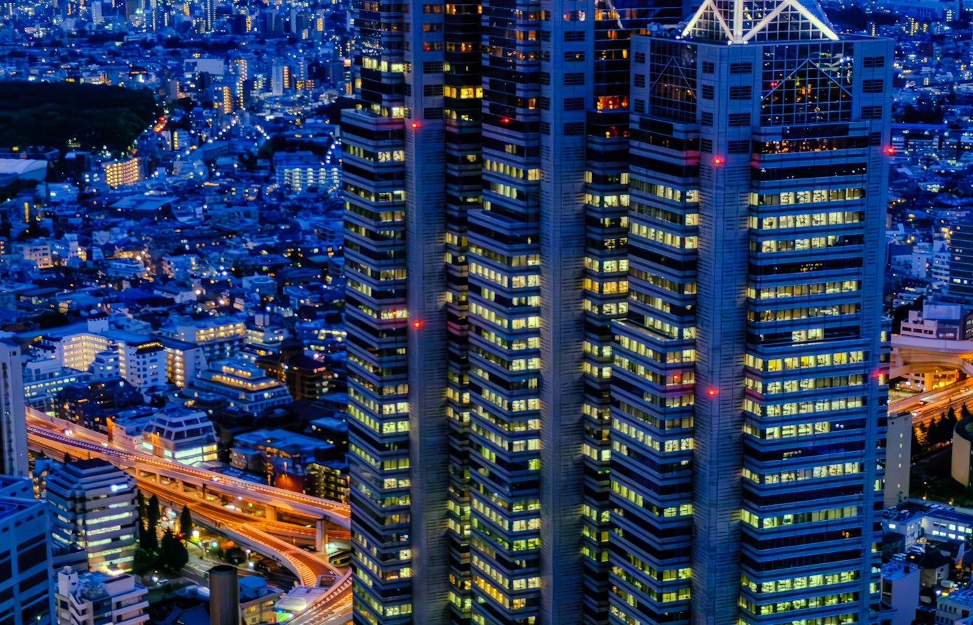 Illuminated high-rise buildings and curving roads in Shinjuku at blue hour