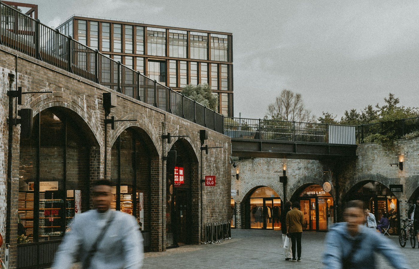 Brick arches and shopfronts at Coal Drops Yard in King's Cross, with cyclists crossing the foreground
