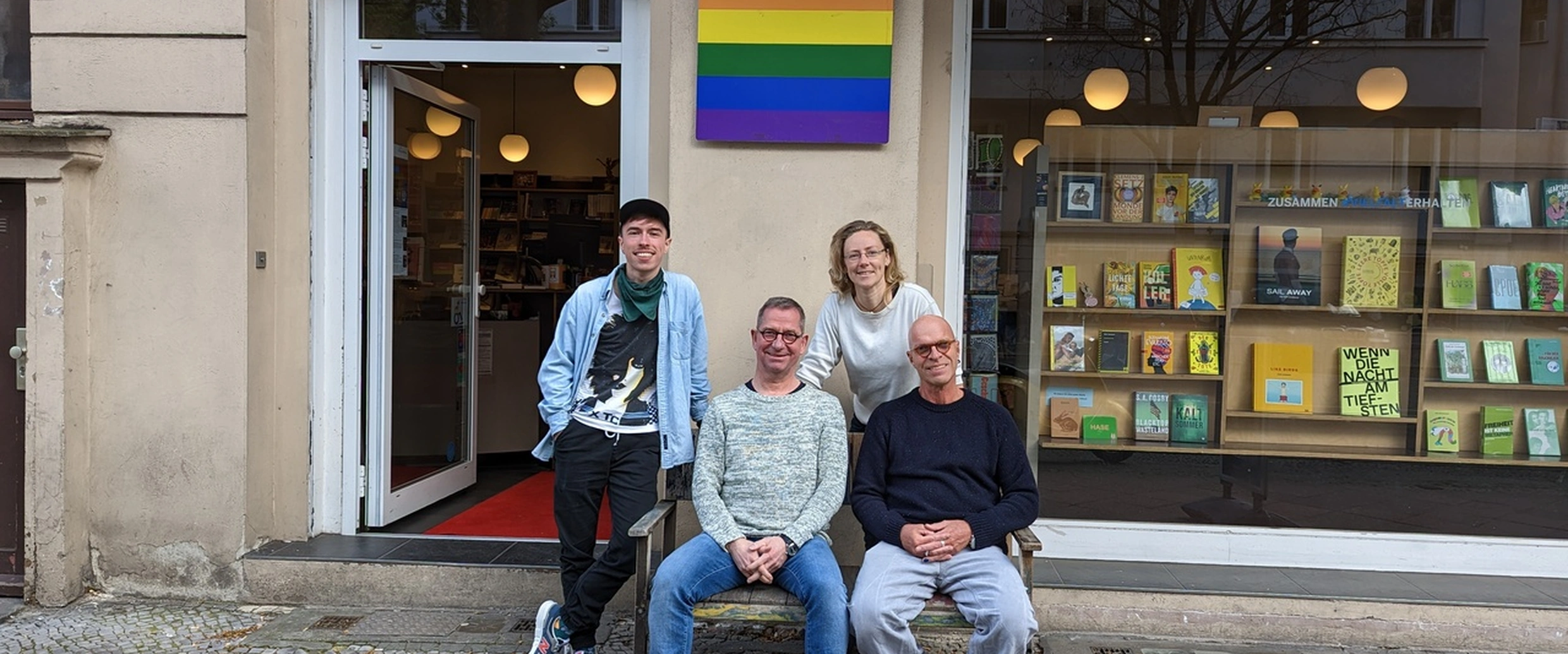 The Eisenherz bookshop team outside the shop on Motzstraße beneath a rainbow flag