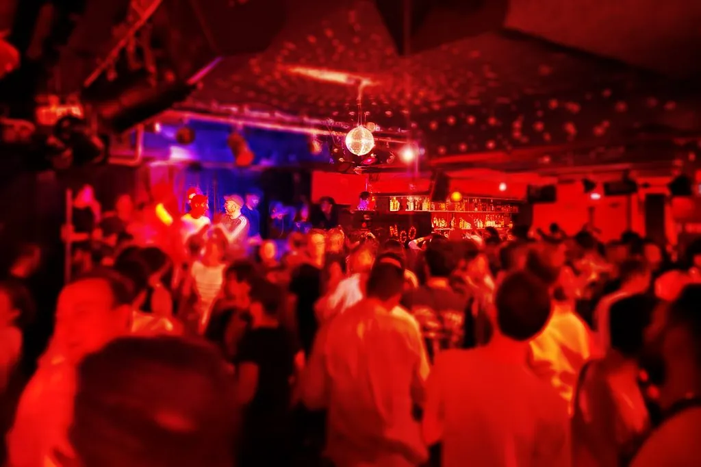 Dancers beneath red lighting and a mirror ball at the Tango in Paris