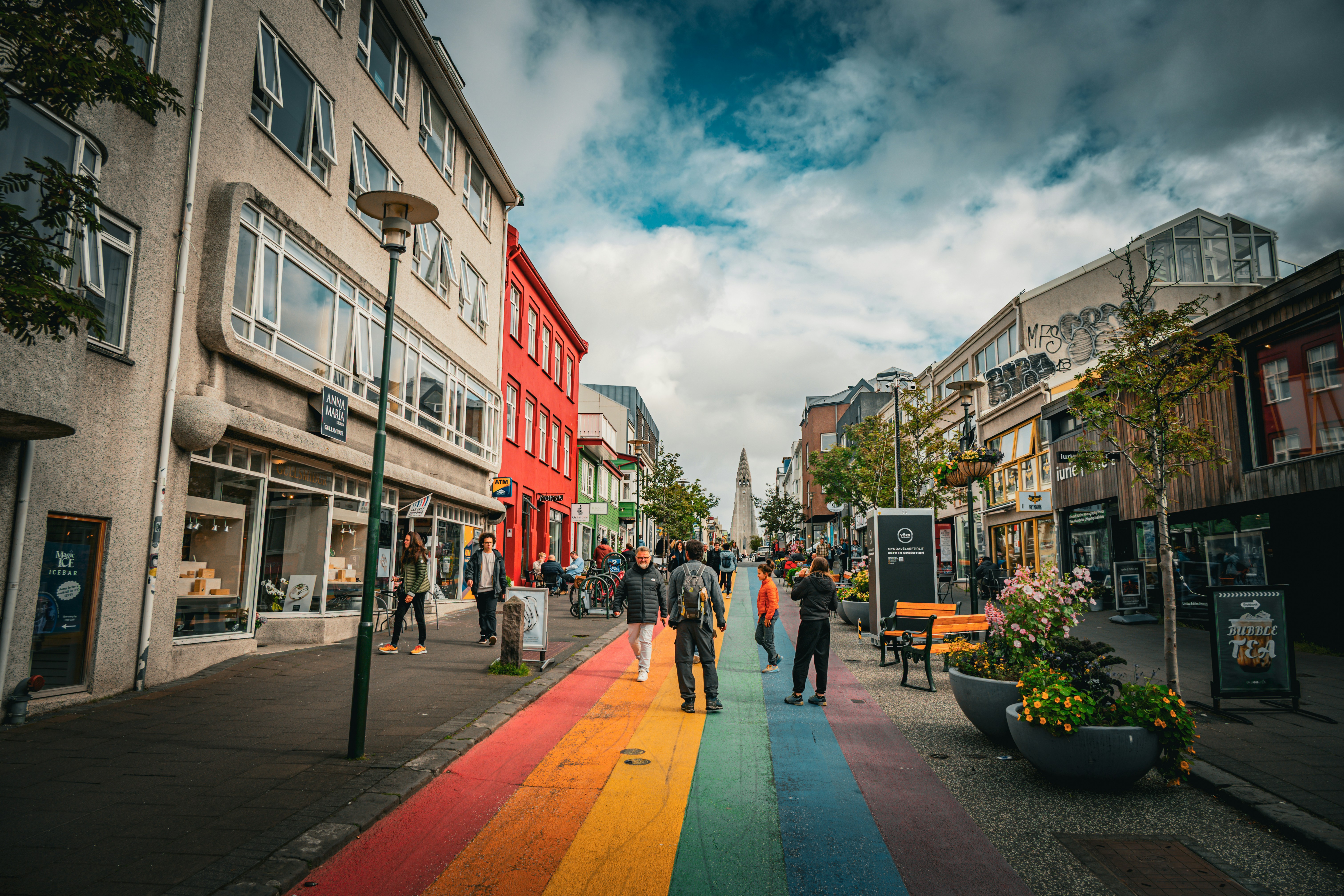 Pedestrians on the rainbow-painted Skólavörðustígur with Hallgrímskirkja in the distance